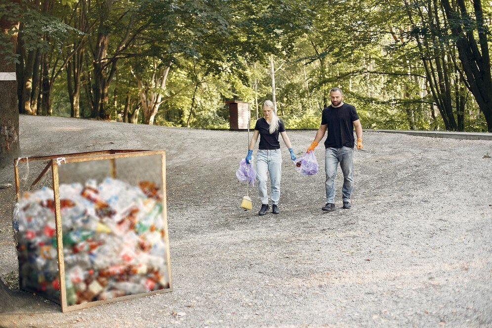 couple-collects-garbage-garbage-bags-park_1157-27402