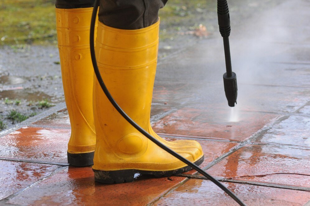 person-wearing-yellow-rubber-boots-with-high-pressure-water-nozzle-cleaning-dirt-tiles_181624-23652